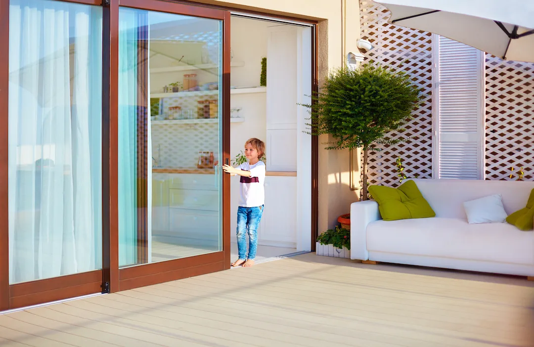 happy young boy, kid opening the sliding door on rooftop patio area at home