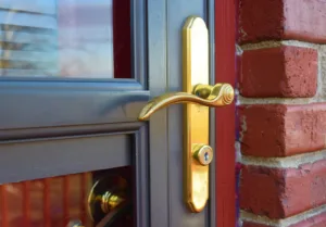 Gold colored door handle to the door of a brick home