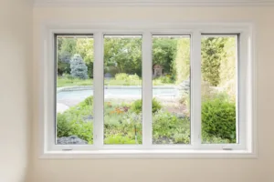 Large four pane window looking on summer backyard with pool and garden