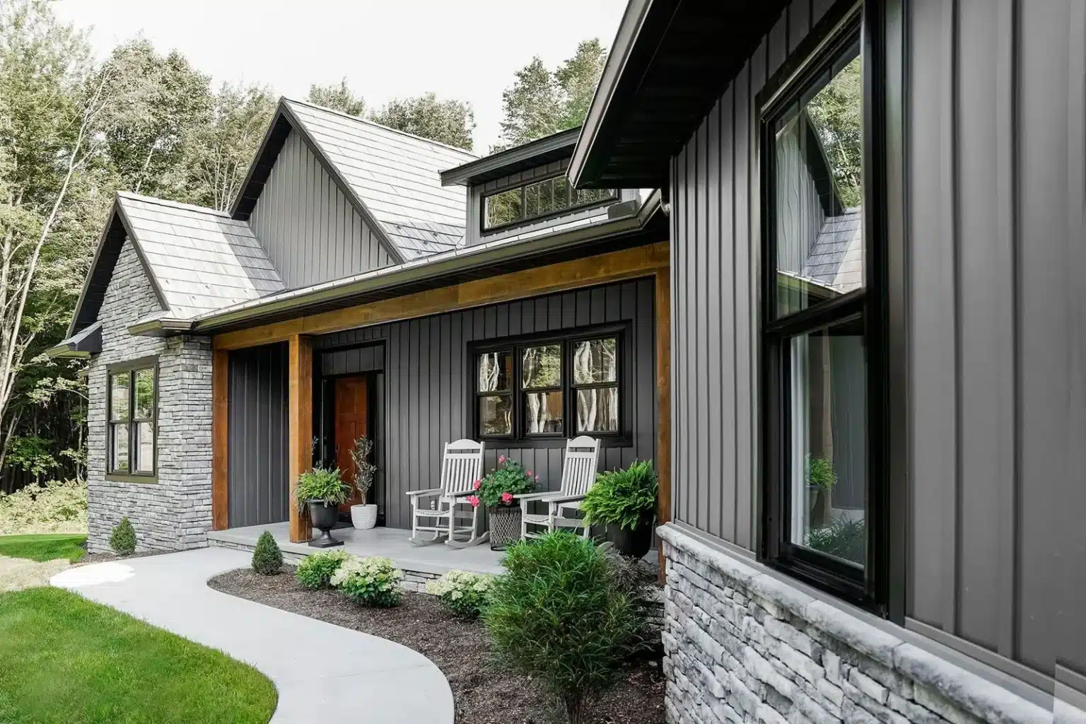 Contemporary home with charcoal siding, black-framed windows, stone accents, and a wood-trimmed front porch.