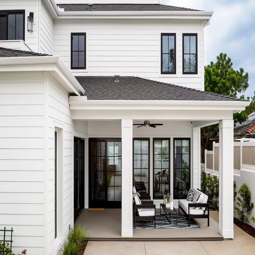 Covered porch with white columns, black-framed glass doors, and outdoor lounge chairs.