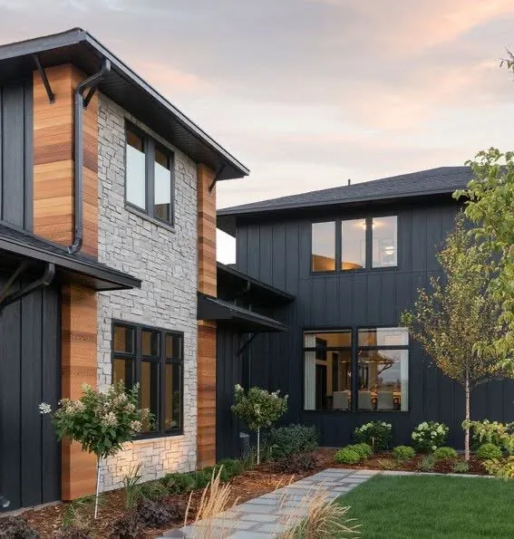 Modern home with dark siding, wood accents, a stone wall, and black-framed windows.