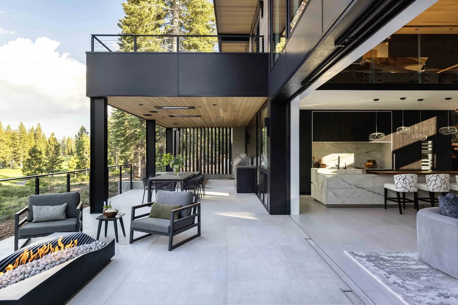 Wide opening connecting a modern kitchen and living area to a covered patio with lounge seating.