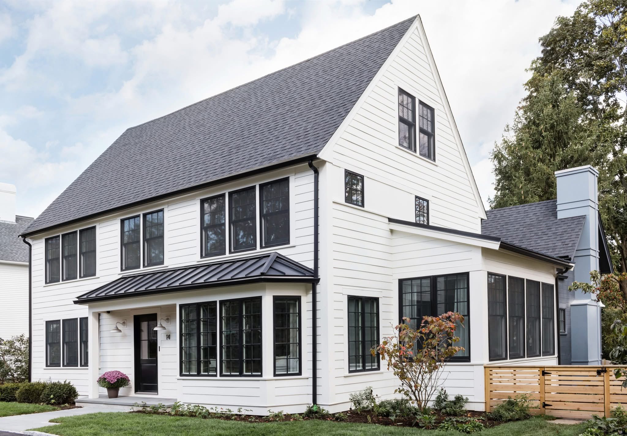White home with black-framed windows, a black front door, and charcoal roofing.